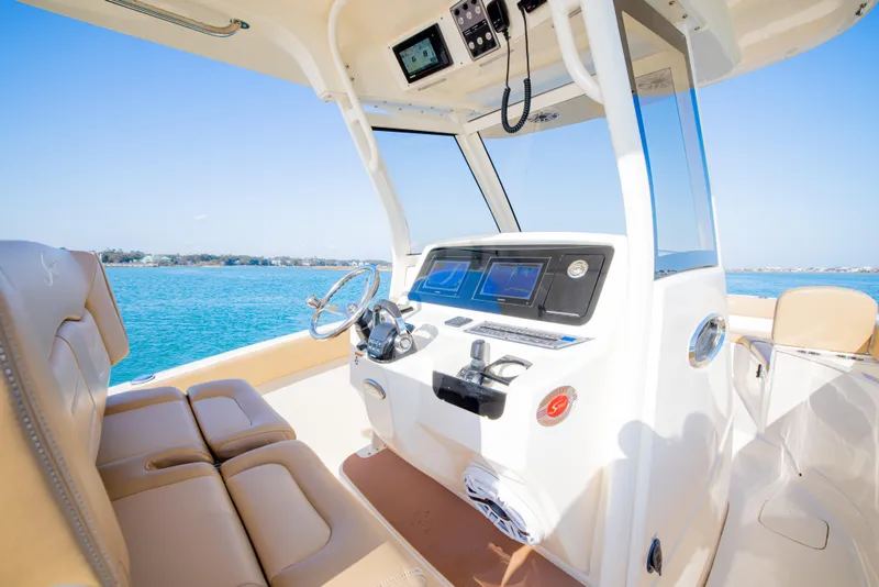 Slide: The Image of 2021 Scout 277 LXF boat interior with modern helm and seating, on a sunny day. - 30