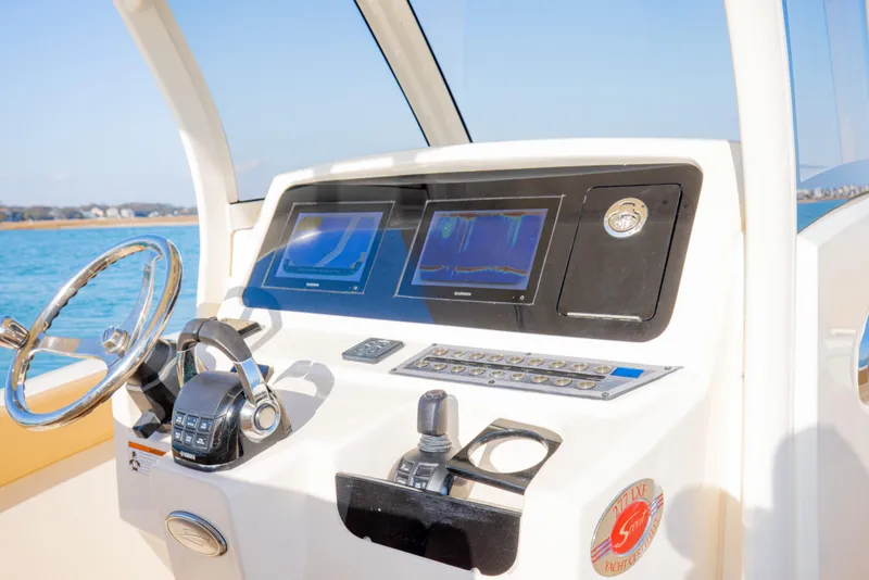 Slide: The Image of 2021 Scout 277 LXF boat dashboard with dual screens and steering wheel. - 37