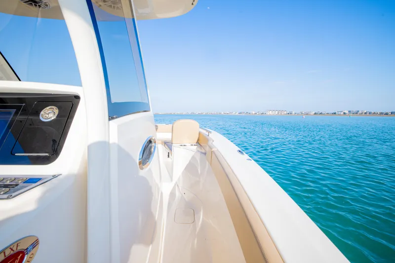 Slide: The Image of 2021 Scout 277 LXF boat cruising on clear blue water. - 38