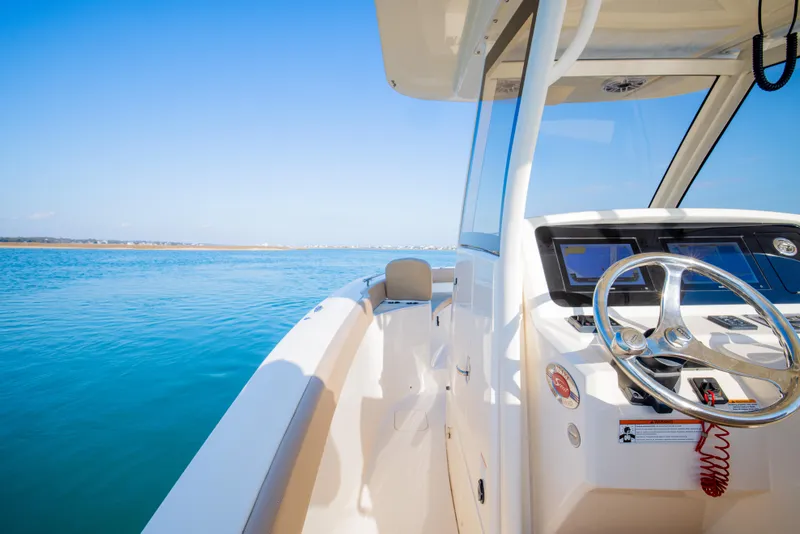 Slide: The Image of 2021 Scout 277 LXF boat on clear blue water, showcasing helm and steering wheel. - 39
