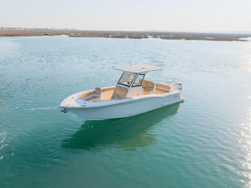 Slide: The Image of 2021 Scout 277 LXF boat on calm water, showcasing sleek design and spacious deck. - 7
