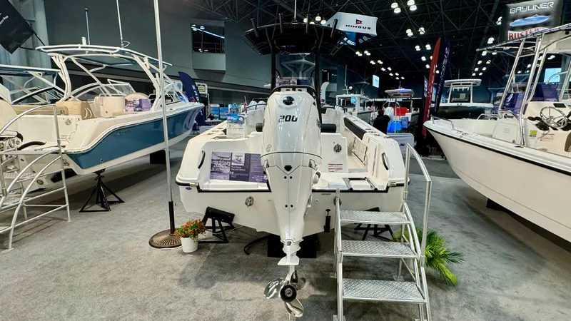 Slide: The Image of 2025 Edgewater 208CC Watchman boat displayed at a boat show with outboard motor. - 2