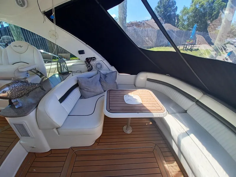 Slide: The Image of 2006 Sea Ray 48 Sundancer interior with white seating, wooden table, and decorative pillows. - 17