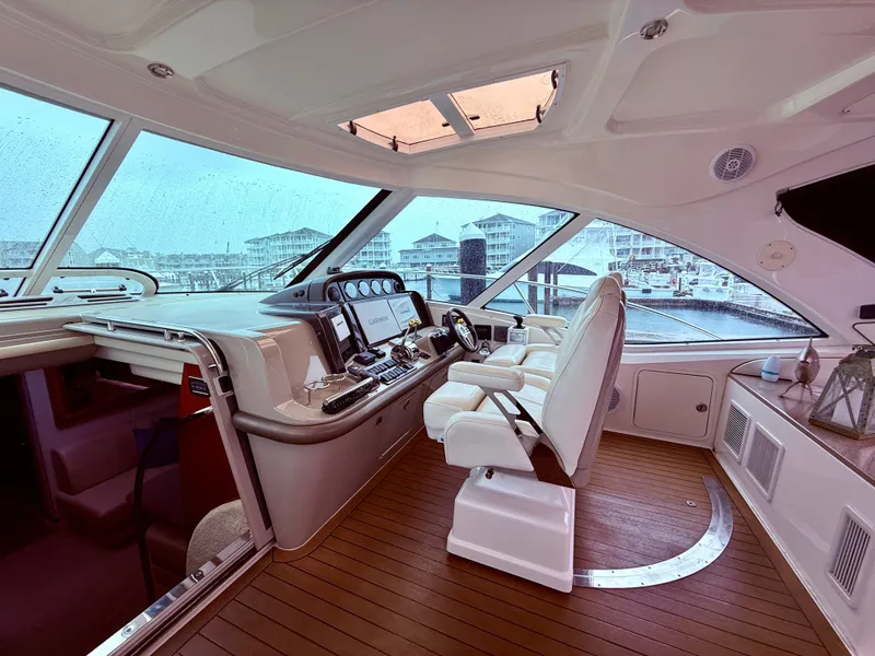 Slide: The Image of 2006 Sea Ray 48 Sundancer helm with modern controls, white seating, and panoramic marina view. - 21