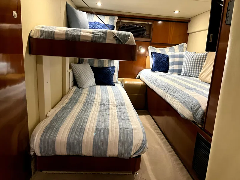 Slide: The Image of 2006 Sea Ray 48 Sundancer cabin with striped bedding and cozy lighting. - 9