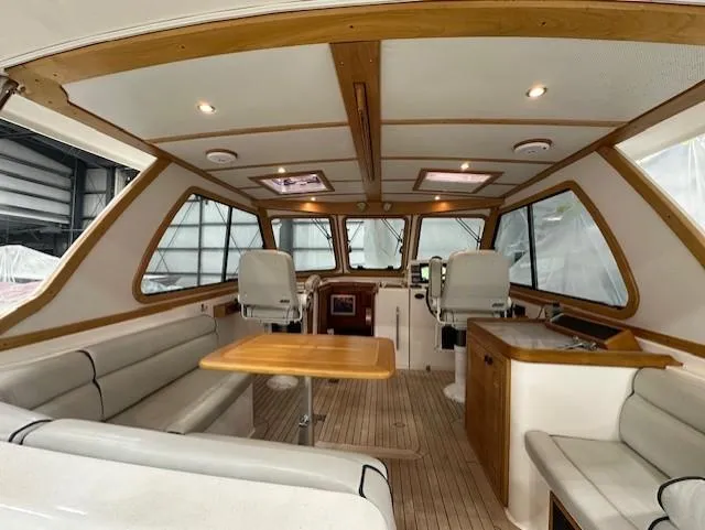 Slide: The Image of 2004 Sabre 42 Express Hardtop interior with seating, table, and helm in a wooden finish. - 22