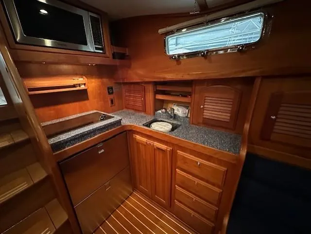 Slide: The Image of 2004 Sabre 42 Express Hardtop yacht interior with wooden cabinetry and modern kitchen amenities. - 34