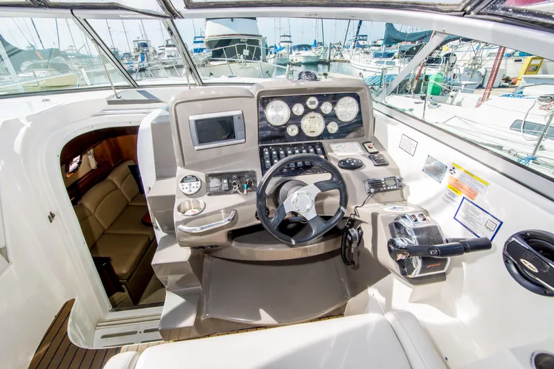 Slide: The Image of 2012 Rinker 310 Express Cruiser helm with modern controls and gauges, docked at marina. - 11