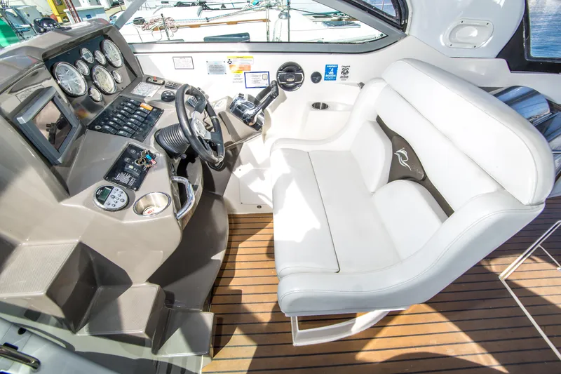 Slide: The Image of 2012 Rinker 310 Express Cruiser helm with white seating and modern dashboard controls. - 12