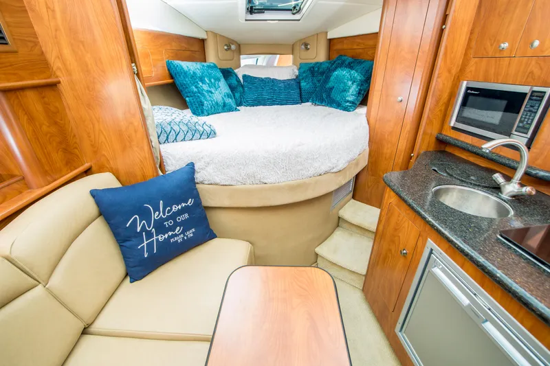 Slide: The Image of 2012 Rinker 310 Express Cruiser interior with cozy bed, kitchenette, and seating area. - 13