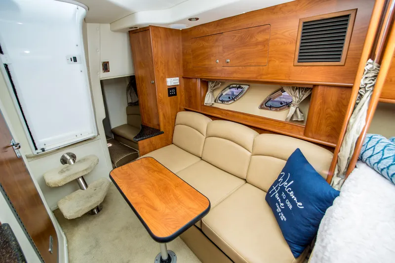 Slide: The Image of 2012 Rinker 310 Express Cruiser interior with beige seating and wooden accents. - 15