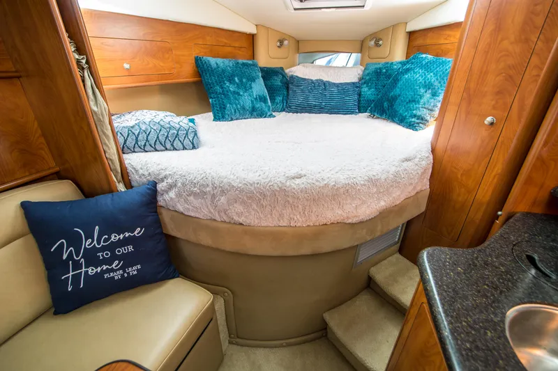 Slide: The Image of Cozy cabin interior of 2012 Rinker 310 Express Cruiser with plush bedding and pillows. - 16