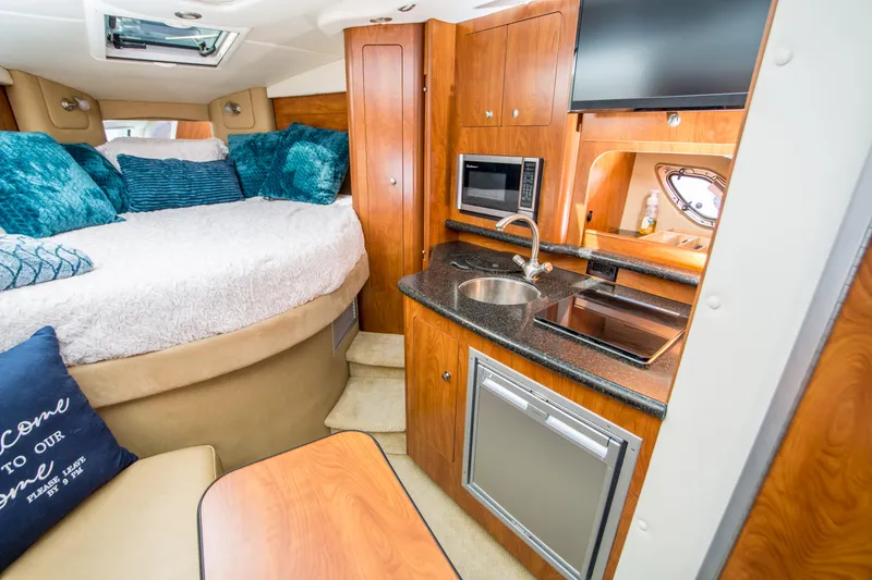 Slide: The Image of 2012 Rinker 310 Express Cruiser interior with bed, kitchenette, and modern amenities. - 17