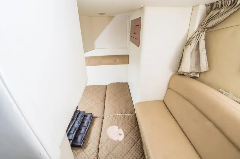 Slide: The Image of 2012 Rinker 310 Express Cruiser cabin interior with beige seating and bedding. - 18