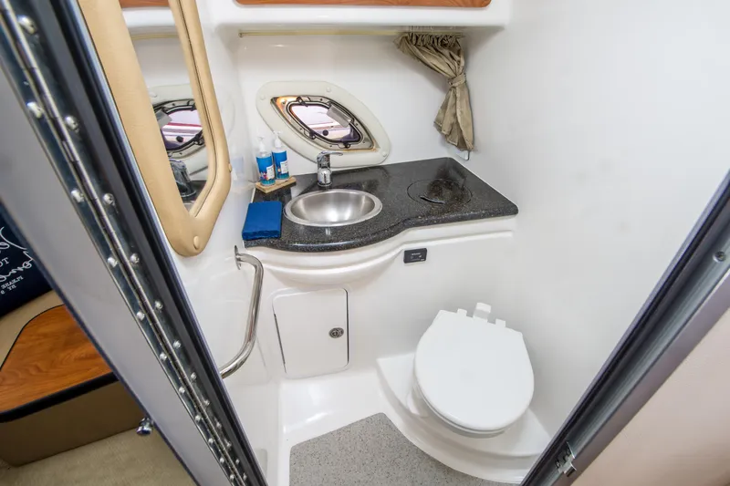 Slide: The Image of 2012 Rinker 310 Express Cruiser bathroom with sink, toilet, and porthole window. - 20