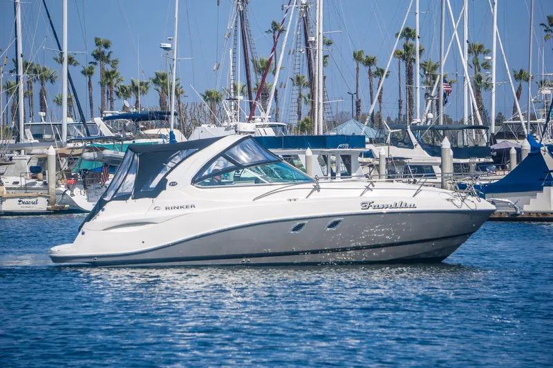 Slide: The Image of 2012 Rinker 310 Express Cruiser in marina, surrounded by sailboats and palm trees. - 3