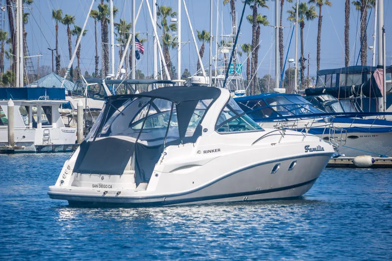 Slide: The Image of 2012 Rinker 310 Express Cruiser docked in a marina with sailboats and palm trees. - 4