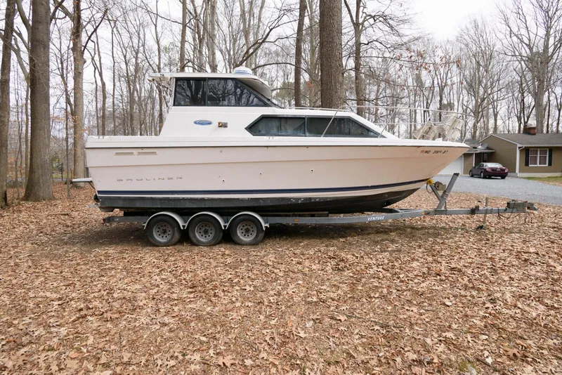 The Image of 2004 Bayliner 289 Classic boat on trailer in wooded area. - 0