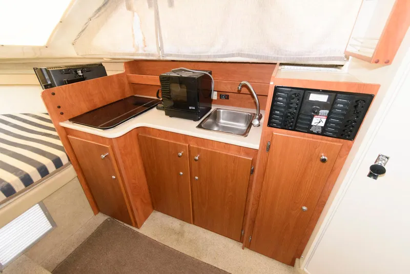 Slide: The Image of 2004 Bayliner 289 Classic boat interior with kitchenette, featuring sink, microwave, and control panel. - 10