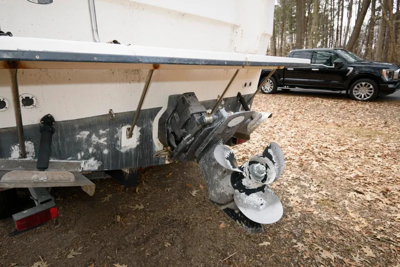 Slide: The Image of 2004 Bayliner 289 Classic boat with damaged propeller, parked on leaf-covered ground. - 14