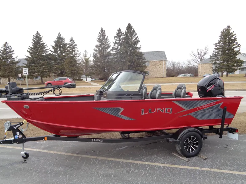 The Image of 2025 Lund 1775 Adventure Sport boat in red, parked on a trailer outdoors. - 0