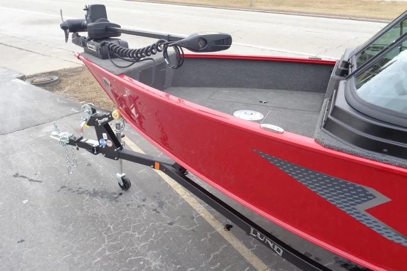 Slide: The Image of 2025 Lund 1775 Adventure Sport boat in red, parked on a trailer. - 2