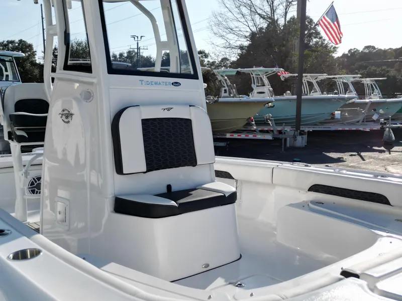 Slide: The Image of 2025 Tidewater 2500CB boat interior, featuring seating and console, displayed outdoors with other boats. - 10