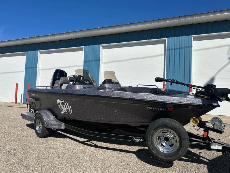 Slide: The Image of 2014 Tuffy 1760 Osprey boat parked outside blue and white building. - 1