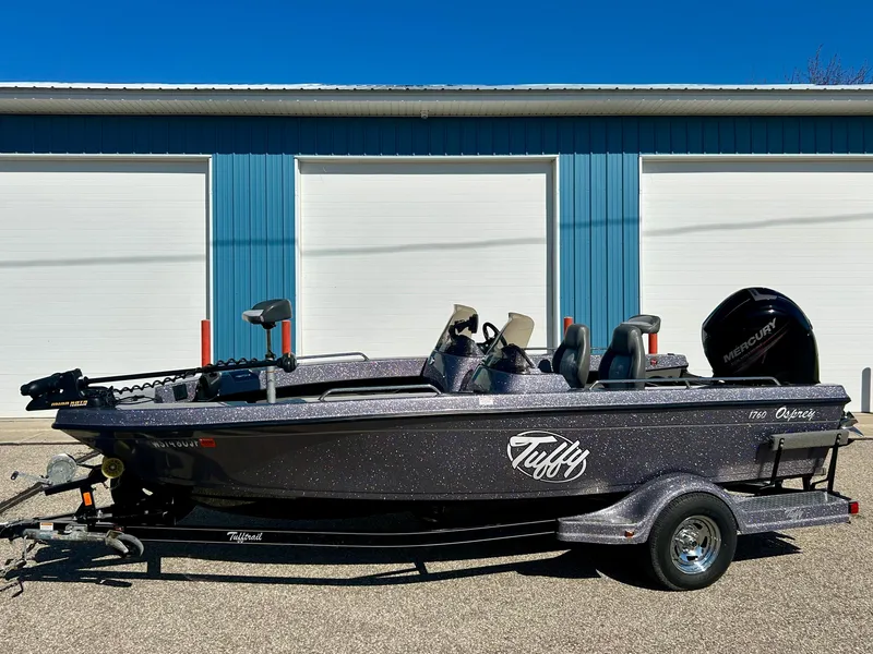 Slide: The Image of 2014 Tuffy 1760 Osprey fishing boat parked outside blue garage doors. - 17