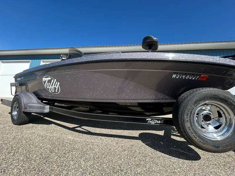 Slide: The Image of 2014 Tuffy 1760 Osprey boat on trailer, parked outdoors under clear blue sky. - 2