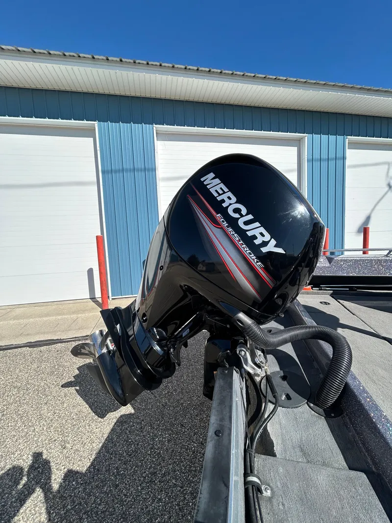 Slide: The Image of 2014 Tuffy 1760 Osprey boat with Mercury outboard motor, parked near blue garage. - 5