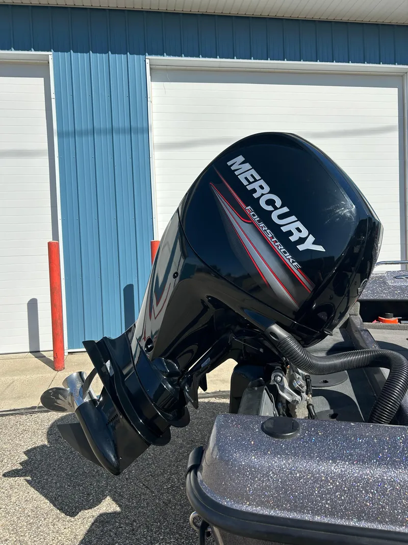 Slide: The Image of 2014 Tuffy 1760 Osprey with Mercury outboard motor, parked near blue building. - 6