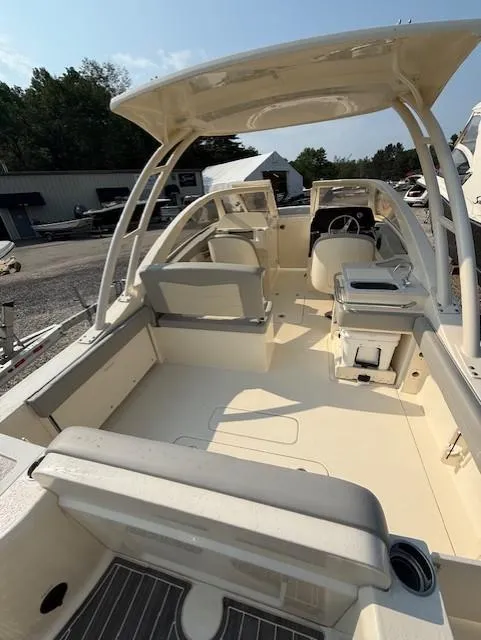 Slide: The Image of 2025 Scout 240 Dorado boat interior with seating and helm, parked outdoors. - 3