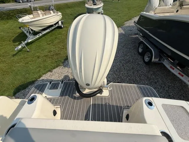 Slide: The Image of 2025 Scout 240 Dorado boat with outboard motor, parked on gravel near other boats. - 4