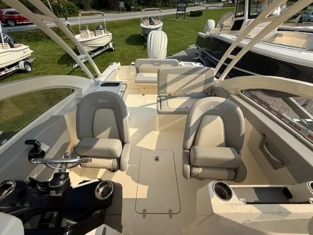 Slide: The Image of 2025 Scout 240 Dorado boat interior with seating and steering wheel, displayed outdoors. - 6