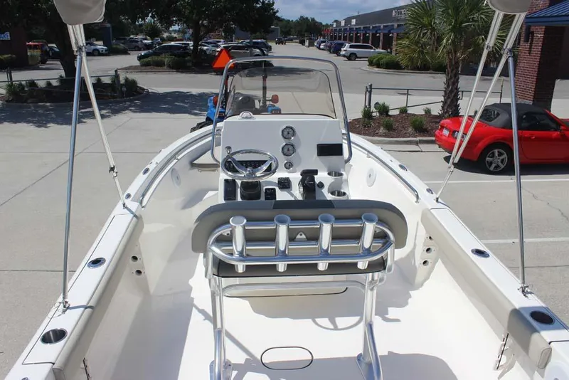 Slide: The Image of 2025 Key West 189 FS boat interior with steering console and rod holders in a parking lot. - 12