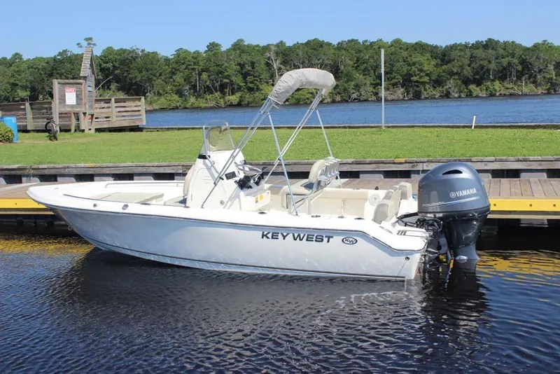 Slide: The Image of 2025 Key West 189 FS boat docked by a scenic riverbank. - 2