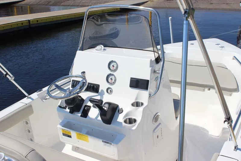 Slide: The Image of 2025 Key West 189 FS boat console with steering wheel and controls, docked by the water. - 7