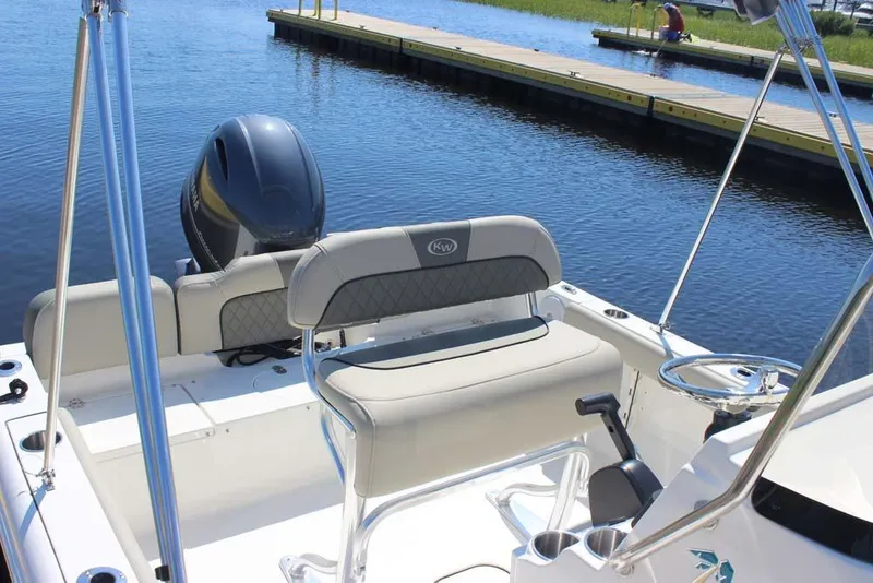 Slide: The Image of 2025 Key West 189 FS boat interior with seating and steering, docked by calm water. - 9