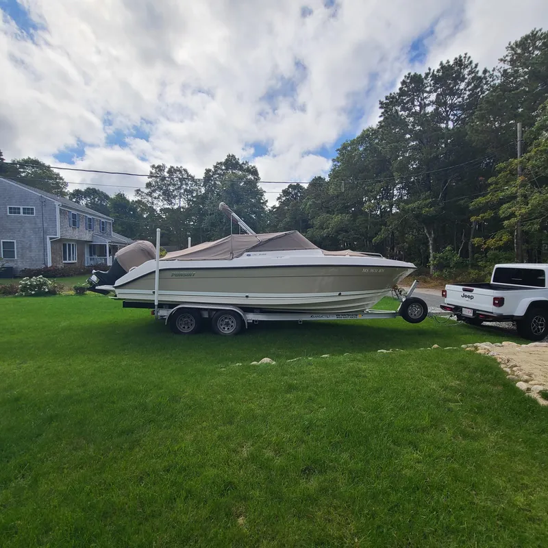 Slide: The Image of 2015 Pursuit DC 235 Dual Console boat on trailer, parked on grass beside a house. - 7