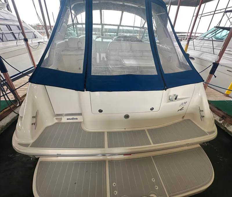 Slide: The Image of 1996 Sea Ray 330 Sundancer boat docked, featuring a spacious rear deck and blue canopy. - 10