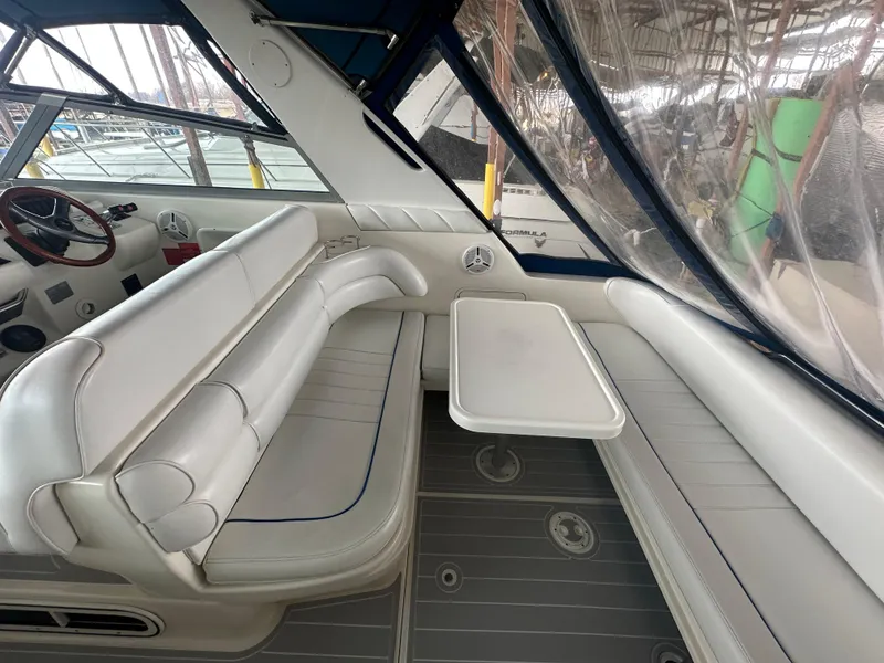 Slide: The Image of 1996 Sea Ray 330 Sundancer interior with white seating and table, docked in marina. - 12