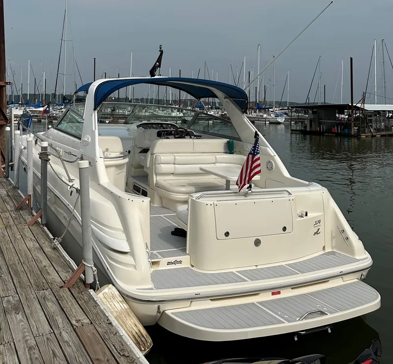 Slide: The Image of 1996 Sea Ray 330 Sundancer docked at marina, featuring American flag and blue canopy. - 2