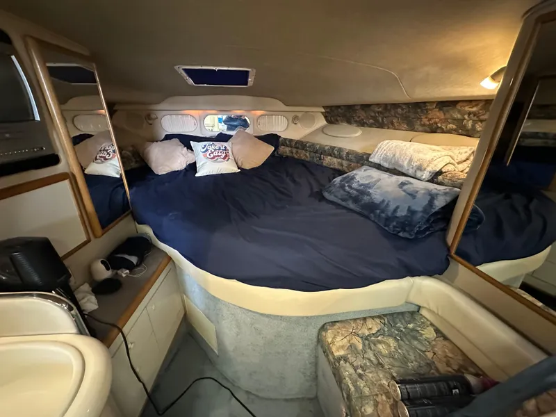 Slide: The Image of 1996 Sea Ray 330 Sundancer cabin interior with cozy bed and pillows. - 27