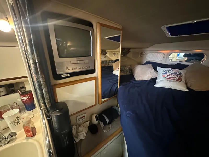 Slide: The Image of Interior of 1996 Sea Ray 330 Sundancer with bed, TV, and cozy decor. - 28