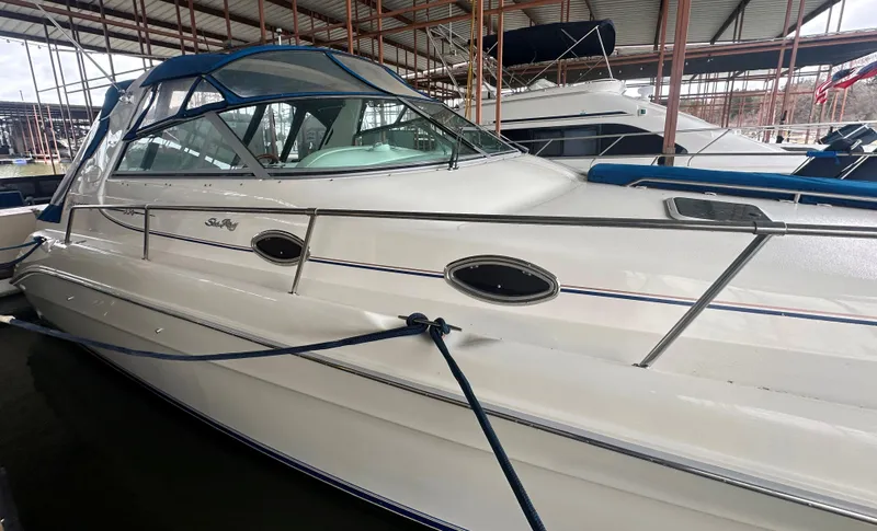 Slide: The Image of 1996 Sea Ray 330 Sundancer boat docked in a marina, featuring sleek design and blue accents. - 9