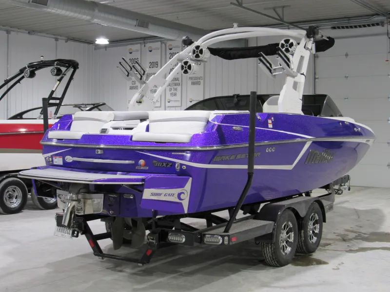 Slide: The Image of 2017 Malibu 22 MXZ boat in a showroom, featuring a vibrant purple exterior. - 2