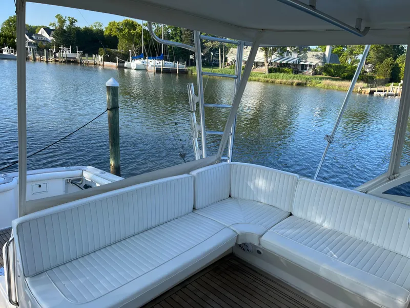 Slide: The Image of 1998 Ocean Yachts 48 Express boat with white seating, docked by a serene waterfront. - 11