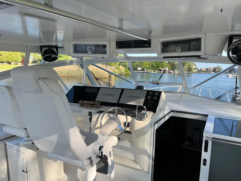 Slide: The Image of 1998 Ocean Yachts 48 Express helm with dual Garmin displays, overlooking serene waters. - 13