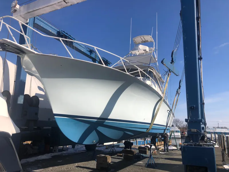 Slide: The Image of 1998 Ocean Yachts 48 Express boat in dry dock, blue hull, clear sky background. - 14